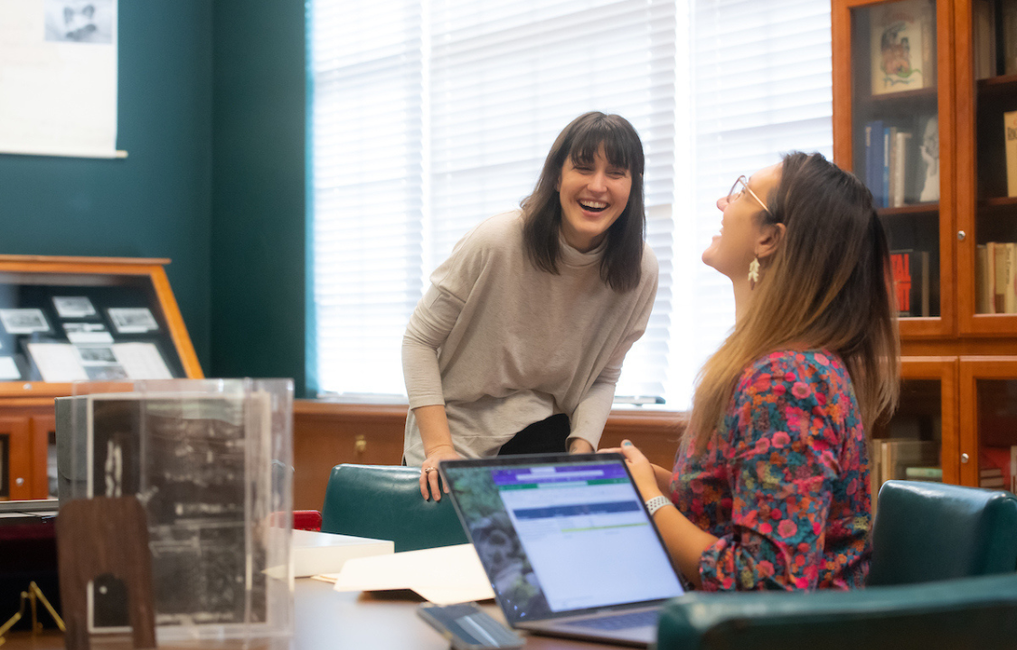 Two people in an office working together and smiling.