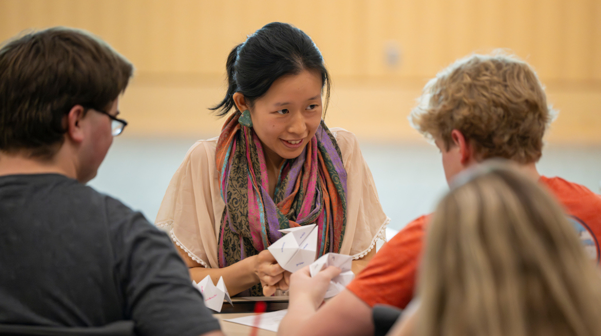 Graduate assistant talking with students in class.