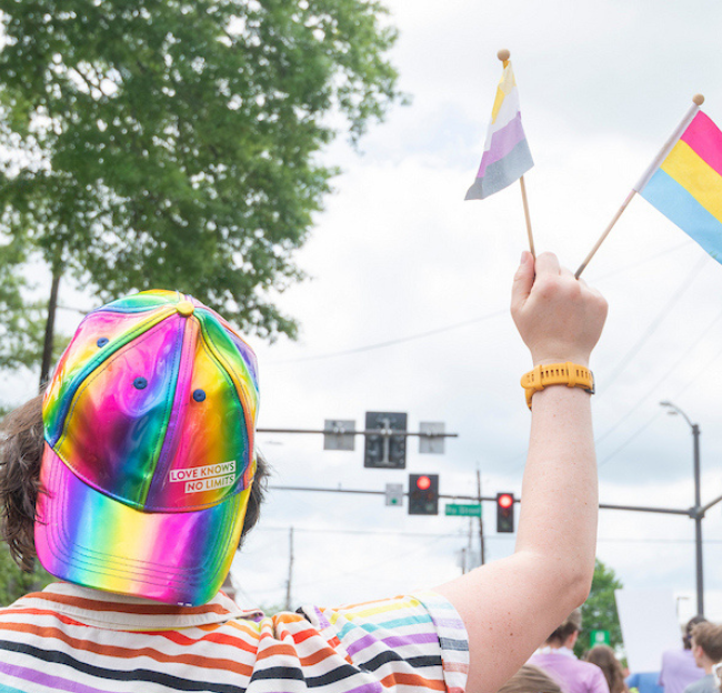 Person holding pride flags in a pride parade.