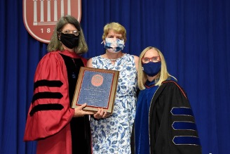 Plaque being received in commencement attire